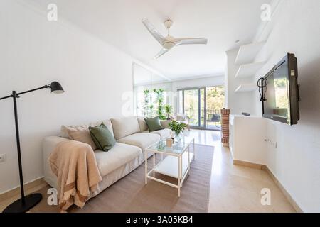 Ein Bild eines Wohnbereichs mit Sofa und wandmontiertem Fernseher im mediterranen Apartment Stockfoto