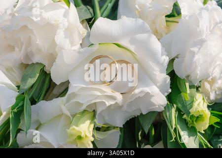Symbol der Liebe und Einheit mit Hochzeitsringen und Blumen Stockfoto