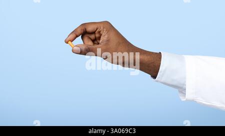 Nahaufnahme der schwarzen Arzthand mit einer einzigen Tablette Stockfoto