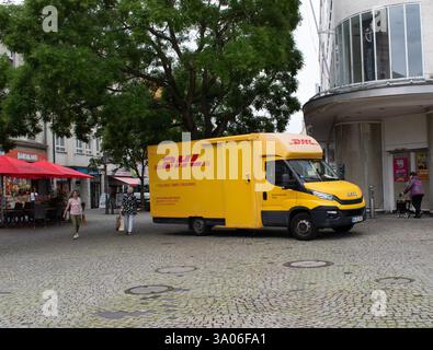 Gelber DHL-Lieferwagen, Kurier, der durch das Stadtzentrum fährt. Stockfoto