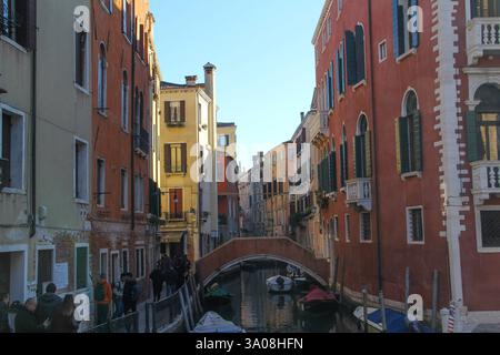Sehenswerte Ansicht eines schmalen Wohnkanals in Venedig, Italien, mit farbenfrohen historischen Gebäuden und festgemachten Booten unter einem klaren blauen Himmel. Stockfoto