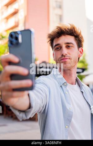 Junger Mann, der ein Selfie mit dem Handy macht Stockfoto