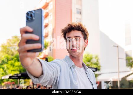 Ein lächelnder junger Mann macht ein Selfie mit dem Handy Stockfoto