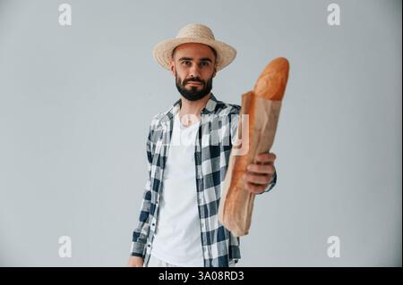 Tourist in Hut halten Baguette. Ein gutaussehender Mann ist im Studio vor weißem Hintergrund. Stockfoto