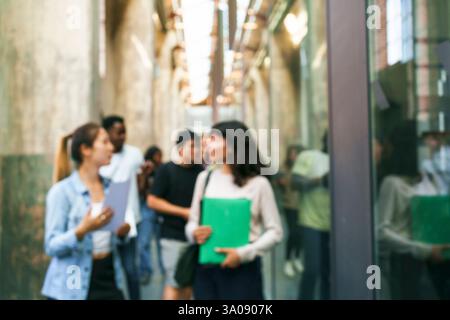 Defokussierte Studenten sprechen während sie im Flur an der Universität laufen Stockfoto