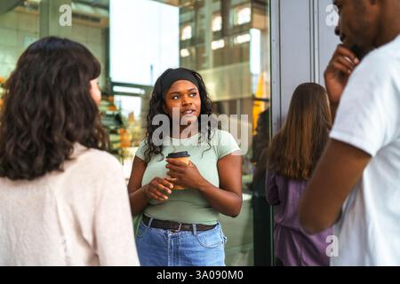 Junge Studentin, die mit Freunden diskutiert, während sie auf dem College-Campus steht Stockfoto