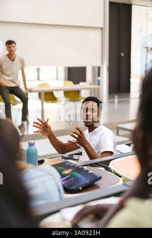 Junger männlicher Student erklärt sich beim Rückblick im Klassenzimmer an der Universität Stockfoto