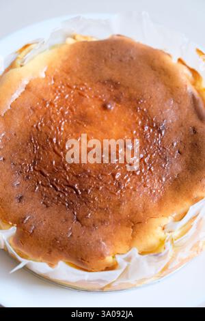 Nahaufnahme von hausgemachtem baskischen Käsekuchen auf einem weißen Teller. Stockfoto