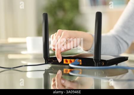 Nahaufnahme einer Frauenhand, die zu Hause das Modem zurückstellt oder anschaltet Stockfoto