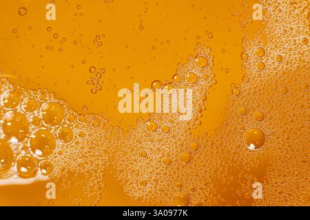Abstrakter orangefarbener flüssiger Hintergrund mit Blasen auf der Oberfläche Pflanzenöl von oben Stockfoto
