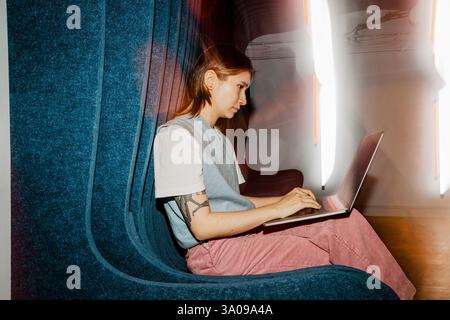 Unternehmerin, die auf dem Sitz sitzt und einen Laptop benutzt Stockfoto
