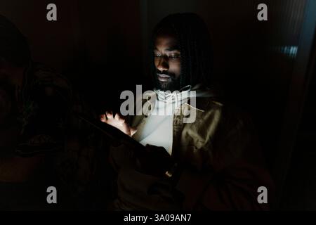 Junger Geschäftsmann, der im Dunkeln über einen Tablet-PC im Internet surft Stockfoto