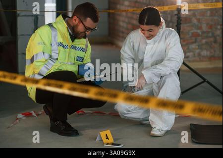 Sitzen und lachen. Zwei Detectives sammeln Beweise an einem Tatort. Forensische Spezialisten machen Fachwissen. Stockfoto