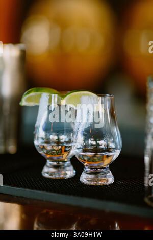 Zwei Tequila-Schüsse mit gesalzenen Rändern und Limettenkeilen auf einer Bar Stockfoto