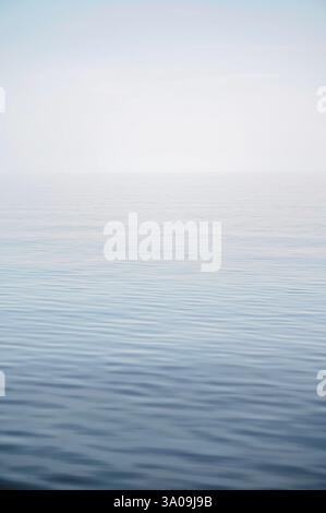 Ruhige Meeresoberfläche mit sanften Wellen unter einem trüben Himmel Stockfoto