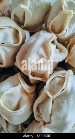 Russische handgemachte Knödel, Produktion. Die rohen Teigtaschen wurden auf ein hölzernes Kochbrett gelegt. Stockfoto