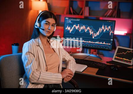 Die weibliche Aktienhändlerin arbeitet mit pc in Innenräumen. Vorstellung von Tausch und Geld. Stockfoto