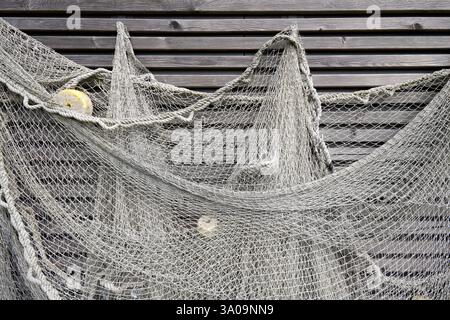 Graues Fischernetz hängt an einer Wand mit Holzlatten Stockfoto