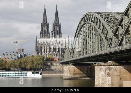Kölner Dom, Eisenbahnbrücke über den Rhein und Kreuzfahrtschiff Stockfoto