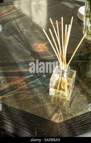 Reed Diffusor auf einem dunklen Holztisch mit Schatten Stockfoto