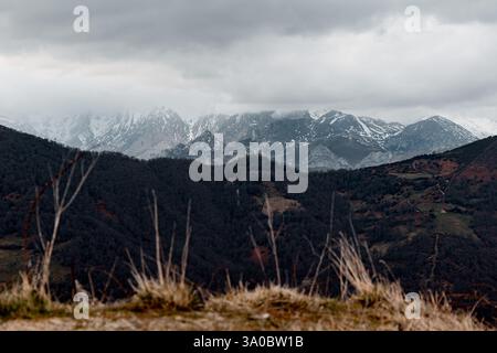 Ein atemberaubender Blick auf die schneebedeckten Berge von Puerto de Pajares, Asturien, Spanien, teilweise bedeckt von Nebel und stürmischen Wolken. Das Vordergrundmerkmal Stockfoto