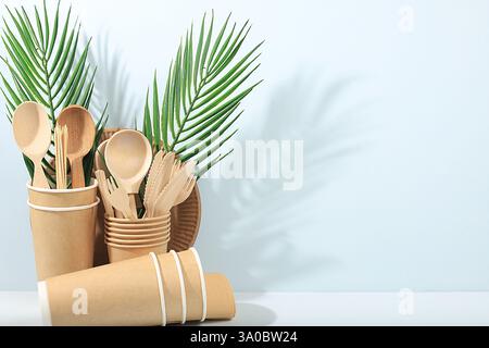 Ein Set umweltfreundlicher Gerichte auf einem sonnigen Tisch. Pappbecher, Teller, Kraftpapierservietten, Grillhalme, Holzgabeln, Löffel und Messer, Stockfoto