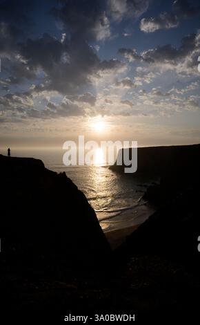 Dramatischer Sonnenuntergang über Tonel Beach mit einer einsamen Figur auf der Klippe Stockfoto