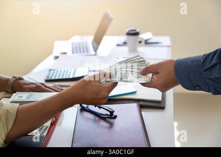 Ein Mann, der Hundert Dollar-Scheine anbietet. Hand eines Geschäftsmannes, der seinem Partner Geld gibt. Hand erhält Geld vom Geschäftsmann. Bestechung, Bestechung, Stockfoto
