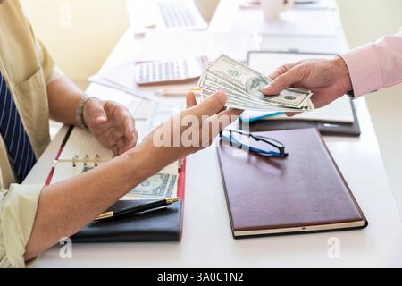 Ein Mann, der Hundert Dollar-Scheine anbietet. Hand eines Geschäftsmannes, der seinem Partner Geld gibt. Hand erhält Geld vom Geschäftsmann. Bestechung, Bestechung, Stockfoto
