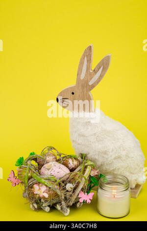 Nest mit Ostereiern und einem Kaninchen auf gelbem Hintergrund. Ostereier. Hochwertige Fotos Stockfoto