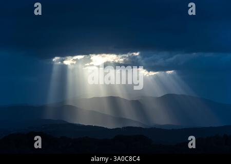SONNENSTRAHLEN DURCH DUNKLE STURMWOLKEN ÜBER DEN KÜSTENBERGEN PALAFOLLS MARESME BARCELONA PROVINZ KATALONIEN SPANIEN Stockfoto
