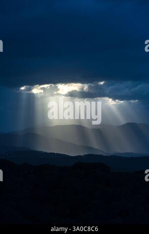 SONNENSTRAHLEN DURCH DUNKLE STURMWOLKEN ÜBER DEN KÜSTENBERGEN PALAFOLLS MARESME BARCELONA PROVINZ KATALONIEN SPANIEN Stockfoto