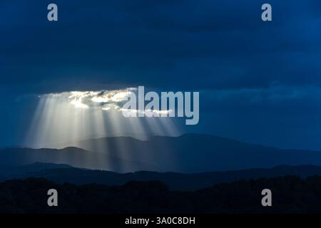 SONNENSTRAHLEN DURCH DUNKLE STURMWOLKEN ÜBER DEN KÜSTENBERGEN PALAFOLLS MARESME BARCELONA PROVINZ KATALONIEN SPANIEN Stockfoto