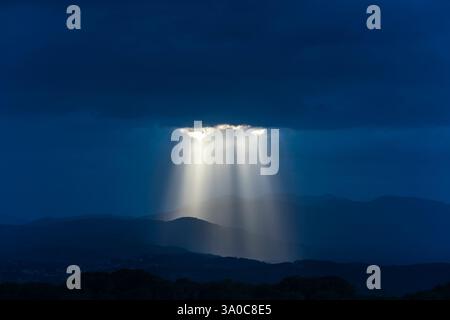 SONNENSTRAHLEN DURCH DUNKLE STURMWOLKEN ÜBER DEN KÜSTENBERGEN PALAFOLLS MARESME BARCELONA PROVINZ KATALONIEN SPANIEN Stockfoto
