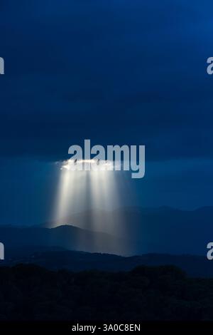 SONNENSTRAHLEN DURCH DUNKLE STURMWOLKEN ÜBER DEN KÜSTENBERGEN PALAFOLLS MARESME BARCELONA PROVINZ KATALONIEN SPANIEN Stockfoto