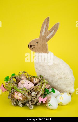 Nest mit Ostereiern und einem Kaninchen auf gelbem Hintergrund. Ostereier. Hochwertige Fotos Stockfoto