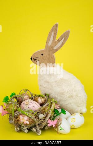 Nest mit Ostereiern und einem Kaninchen auf gelbem Hintergrund. Ostereier. Hochwertige Fotos Stockfoto