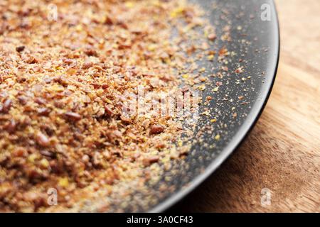 Gemahlene Flachssamen in schwarzer Platte auf Holztisch. Gemahlene getrocknete organische Zutat. Braunes nahrhaftes gesundes Superfood. Stockfoto