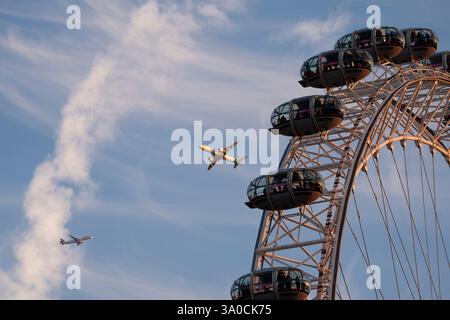 Zwei Flugzeuge fliegen während Sonnenuntergang über das London Eye. Bilddatum: Montag, 3. März 2025. Stockfoto