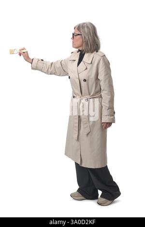 Seitenansicht einer Frau, die mit einem Pinsel auf weißem Hintergrund malte Stockfoto