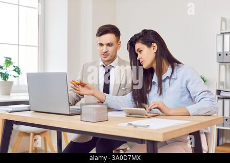 Junge positive weibliche Bürokollegen, die als Team am Laptop im Coworking-Bereich arbeiten, Buchhaltung Stockfoto