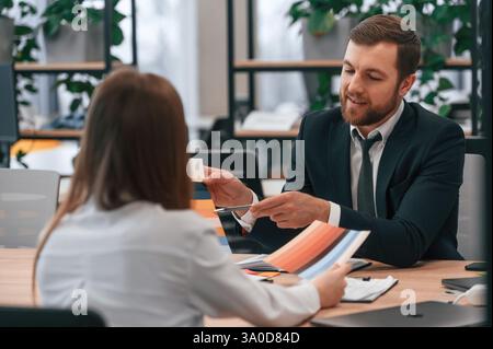 Ein Mann im Anzug arbeitet mit einer Frau im Büro. Stockfoto