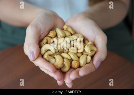 Cashewnüsse. Nahaufnahme weiblicher Hände mit einem Haufen Cashewnüsse. Stockfoto