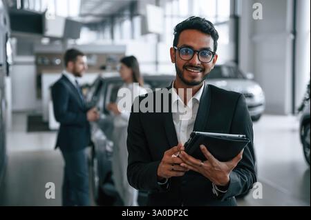 Mann, der vor seinen Kollegen steht. Drei Personen arbeiten im Ausstellungsraum zusammen. Stockfoto