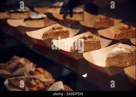 Nahaufnahme der Hände des Mannes in Handschuhen, die köstliche Desserts nehmen. Stockfoto