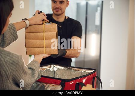 Der Mann gibt der Frau eine Menge Öko-Kisten mit Essen. Stockfoto