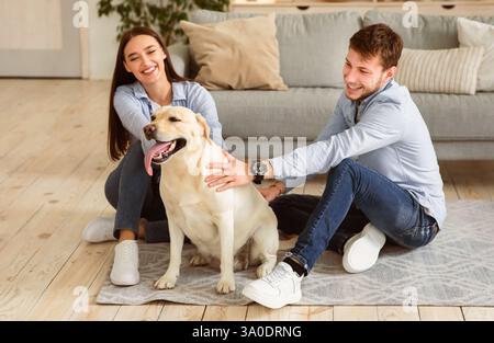 Junge glückliche Familie von zwei sitzen auf dem Boden mit Hund Stockfoto