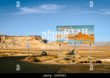 Horizontales Bild des Willkommensschilds von Utah mit der Aufschrift „Willkommen in Utah“ mit dem Auto, das auf einer langen Straße fährt. Stockfoto