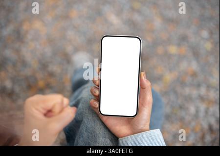 Eine Nahaufnahme der rechten Hand, die das Smartphone hält, während die linke Hand im Kreuz sitzt. Videos ansehen oder Live-Streaming. Stockfoto