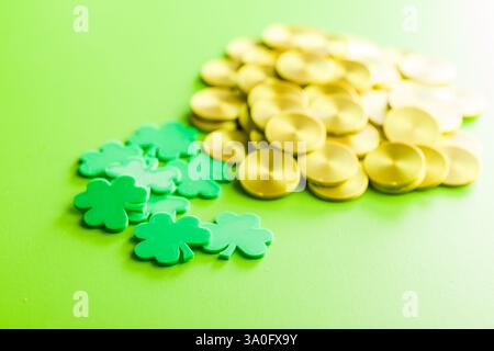 St. Patrick's Day. Grüner Kleeblatt hinterlässt Dekoration und Goldmünzen auf grünem Hintergrund. Stockfoto